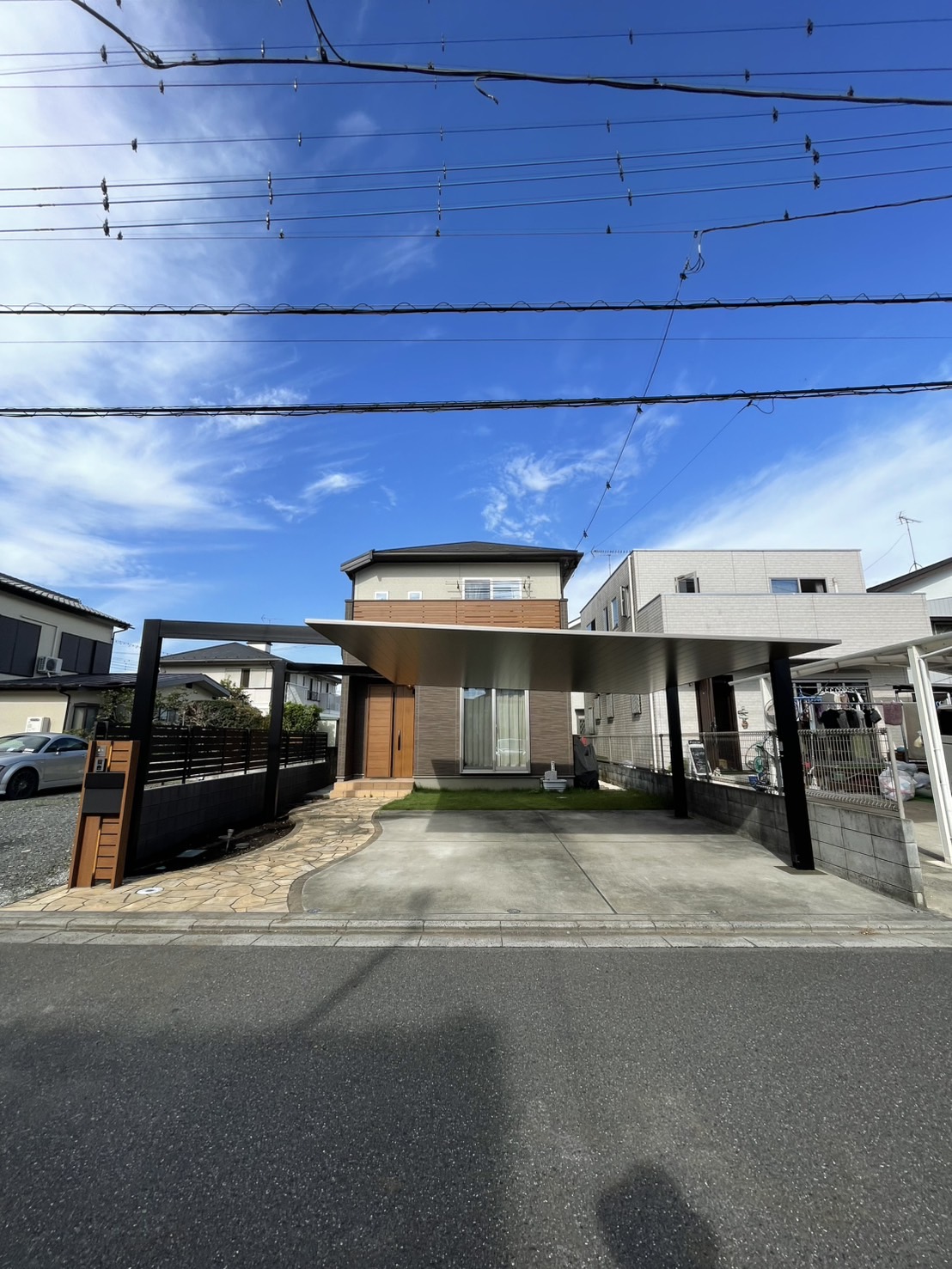 フラット屋根のカーポートとアルミ格子の門扉、人工芝を組み合わせた住宅外構の全景